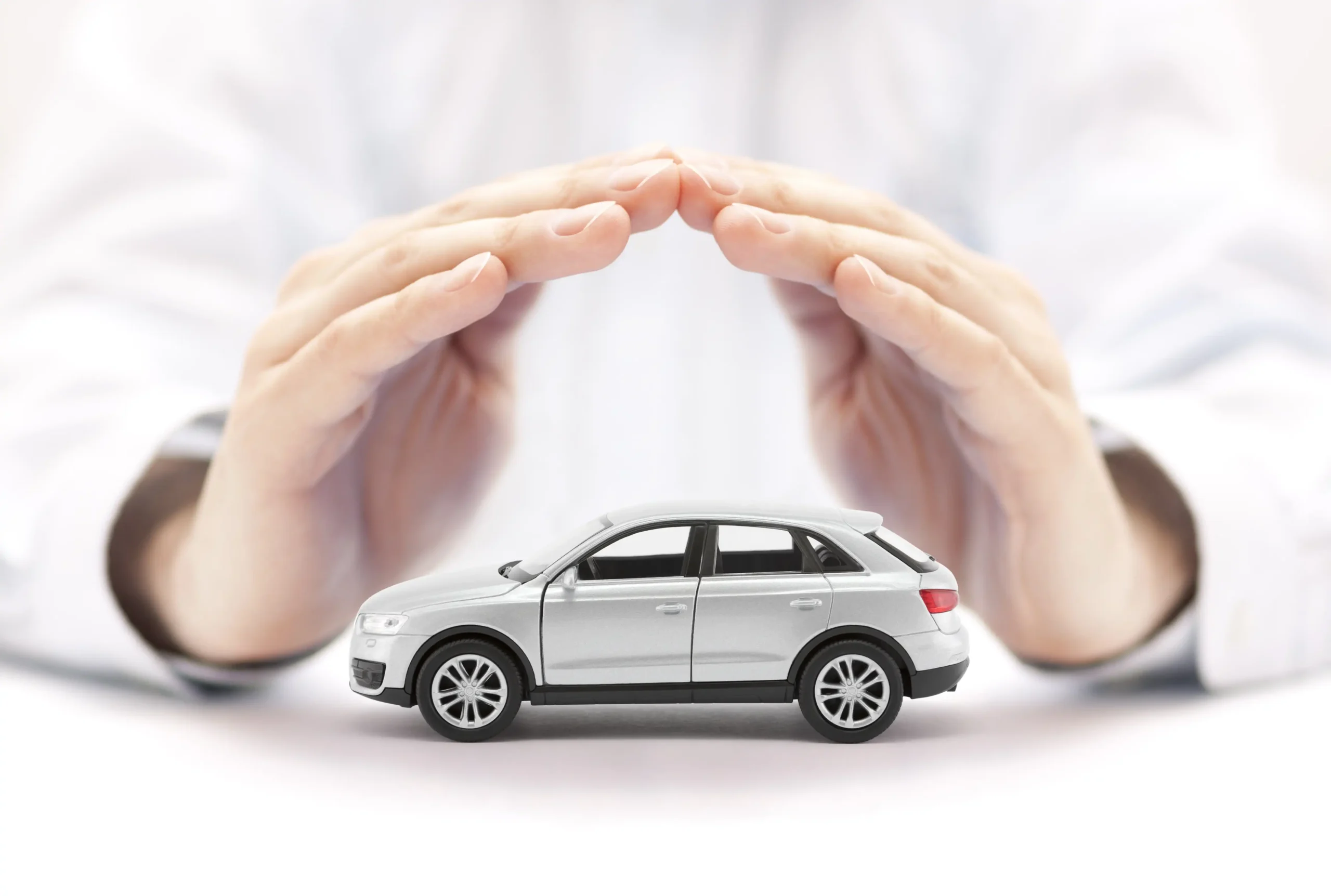 Protection de Véhicule : Sécurité et Assurance Auto Main protectrice couvrant une voiture miniature, symbolisant la protection automobile
