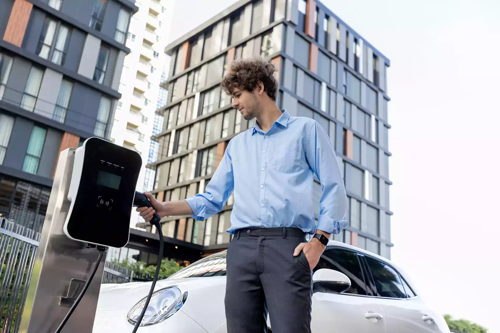recharge-vehicule-electrique-entreprise-transition-energetique-ocean.webp Homme rechargeant une voiture électrique sur une borne, symbolisant la transition énergétique et la mobilité durable en entreprise.