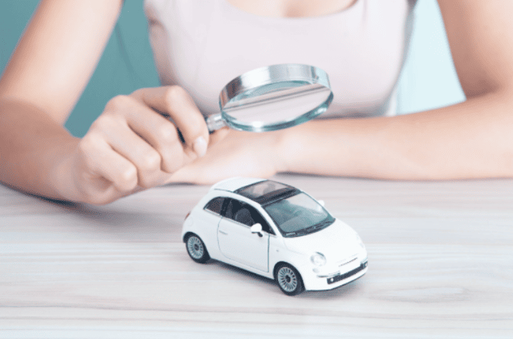 analyse-vehicule-gestion-flotte-controle-entreprise-ocean.png Main tenant une loupe au-dessus d’un véhicule miniature, illustrant l’analyse, le contrôle et la gestion de flotte automobile en entreprise.